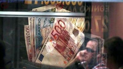 An advertisement featuring Greek euro currency notes are seen through a metro train window in Athens, Greece. Kostas Tsironis/Bloomberg