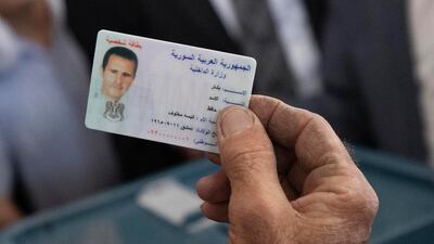 An election official checks President Al Assad's ID, at the polling station where the Syrian leader had gone to vote. AP