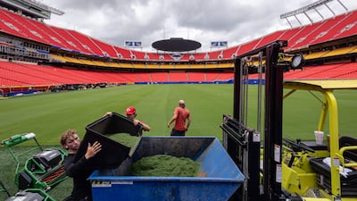 Grounds crew members dump freshly trimmed grass taken from the pitch at Kansas City Stadium ahead of the 2026 World Cup. AFP