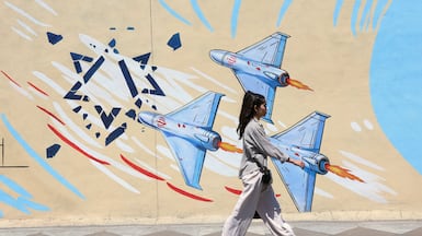 An Iranian girl walks past an anti-Israeli mural on a street in Tehran. EPA