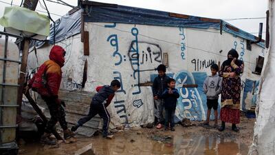 Syrian refugee children walk between tents in mud from a heavy rain at a refugee camp in the town of Bar Elias, in Lebanon's Bekaa Valley. AP