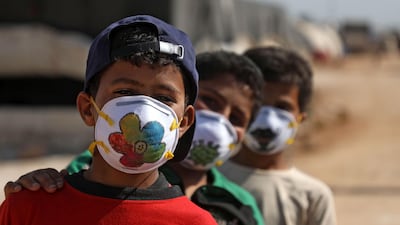 Displaced Syrian boys pose while wearing face masks decorated by artists during a Covid-19 awareness campaign at the Bardaqli camp in the town of Dana in Syria's north-west Idlib province. AFP