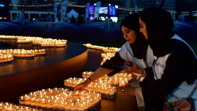 Two women light candles after the building lights were switched off for the Earth Hour environmental campaign in Dubai on March 24, 2018. Earth Hour, which started in Australia in 2007, is set to be observed by millions of supporters in 187 countries, who will turn off their lights at 8.30pm local time in what organisers describe as the world's "largest grassroots movement for climate change". / AFP PHOTO / Giuseppe CACACE