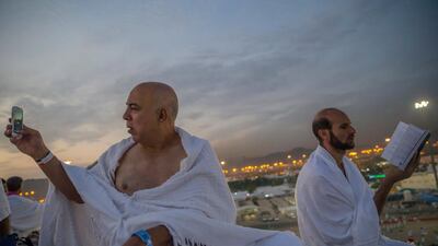 A Muslim pilgrim reads the Quran as another pilgrim takes a photo. AP Photo