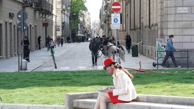 A woman wearing a protective face mask reads a book in Carignano square, Turin, Italy. EPA