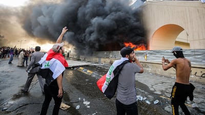 Protesters gather next to a burning building amid clashes with Iraqi riot police between the capital Baghdad's Tahrir Square and the high-security Green Zone district. AFP
