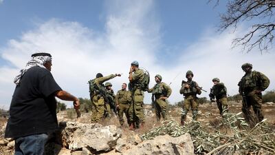 Israeli soldiers stand near a Palestinian farmer waiting to reach a farm to harvest olives in an olive grove on the outskirts of the West Bank village of Yetma, near the Jewish settlement of Rehelim, near Nablus. EPA