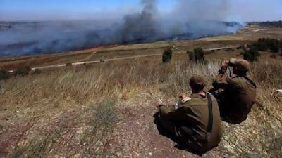 Israeli soldiers north of the Golan Heights watch the Syrian border through smoke, allegedly caused by Syrian mortar shells, after some shells landed on the Israeli side of the border.