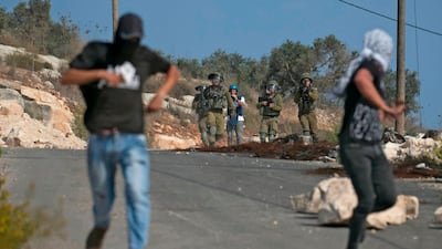 Palestinian protesters run from Israeli soldiers near the Jewish settlement of Qadumim in the Israeli-occupied West Bank on November 8. Jaafar Ashtiyeh / AFP