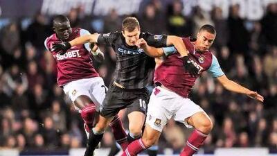 Manchester City's Bosnian forward Edin Dzeko, centre, tussles with West Ham's New Zealand defender Winston Reid, right, and Senegalese midfielder Mohamed Diame at Upton Park. Glyn Kirk / AFP