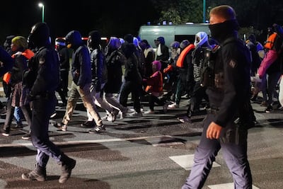 French police escort a group near a canal in Gravelines where migrants were trying to board a boat to cross the Channel. PA