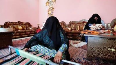 Hamda Al Mazrouei weaves a tablecloth while her mother Shamsa Al Mazrouei weaves a traditional basket in Madinat Zayed. Sarah Dea / The National