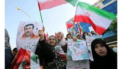 Lebanese Hezbollah supporters carry Iranian flags and posters of Iranian President Mahmoud Ahmadinejad upon his arrival at the main airport road in Beirut.