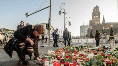 A mourner placing a candle on December 21, 2016 at a makeshift memorial near the Kaiser Wilhelm Memorial Church in Berlin, close to the site where a truck crashed into a Christmas market two days before. Twelve people were killed and almost 50 wounded, 18 seriously, when the lorry tore through the crowd on December 19, 2016. Clemens Bilan/AFP