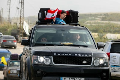 The Lebanese flag is flown as displaced residents make their way back to their homes on a makeshift road, built at the site where the Qasmiyeh bridge was destroyed by Israeli attacks in the southern Lebanese area of Al Qasmiyeh on April 18, 2026. AFP