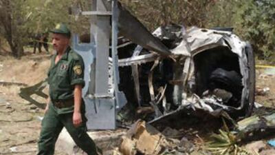 A soldier passes a car damaged by the explosion, after a suicide car bomber rammed into a police academy, in the town of Les Issers, east Algeria, yesterday.