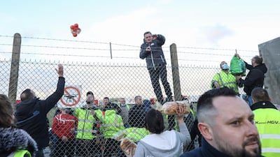 Volunteers throw fresh food and supplies over a perimeter fence to truck drivers at Manston airport in Manston, U.K. Routes to Dover, Britain's busiest cross-channel port, have been choked for days after France shut its border with Britain, blaming an outbreak of a novel strain of the coronavirus. Bloomberg