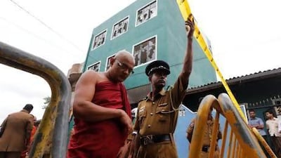 A Sri Lankan Buddhist monk walks past a vandalised mosque in Colombo as police man a barricade.