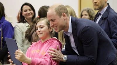 Prince William poses for photos with a young Ukrainian resident. Reuters