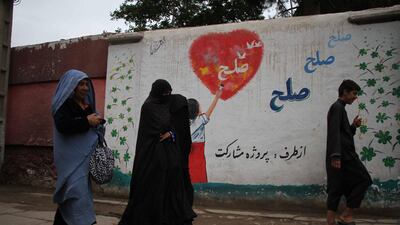 Afghan women pass by a wall with graffiti reading 'Peace' in Herat, Afghanistan. EPA