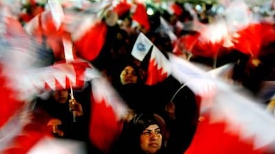 Bahraini women wave the national flag during an election rally for the opposition in Manama.