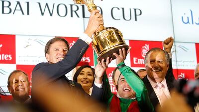 Trainer Graham Motion, left, jockey Joel Rosario hoist the Dubai World Cup in Dubai after a victorious win by Animal Kingdom. (Sarah Dea / The National)