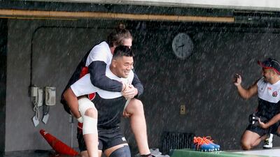 Japan's rugby team player Jiwon Koo, carries teammate James Moore in a flooded walkway at a stadium in Tokyo as the team practices ahead of their match against Scotland. AP