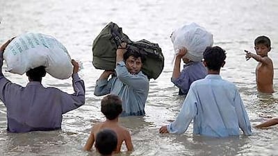Flood victims carry their belongings through floodwaters in Pakistan's Sindh province yesterday.
