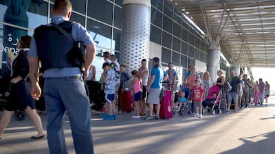 A security stands guard as tourists queue outside the Enfidha international airport to leave Tunisia. Kenzo Tribouillard / AFP