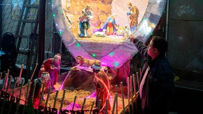 An Egyptian Christians worshipper stands by a nativity scene as he attends the Christmas Eve mass at the Coptic Catholic St. Mark Church in Minya city. AFP