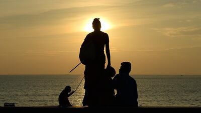 A woman with her pet monkey asks for alms from a couple sitting on the seafront in Mumbai. Punit Paranjpe / AFP