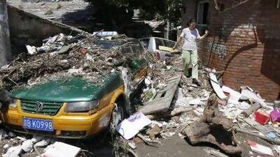A resident walks past debris and a taxi damaged by floodwaters after heavy rainfall hit the Mentougou District in Beijing.