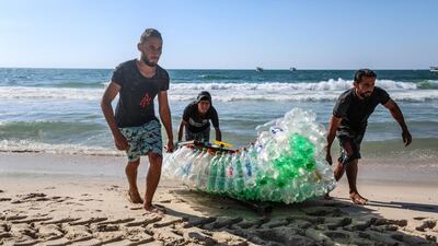 Mohammed Abu Zeid (left) and Mouath Abu Zeid (right), fishermen from Gaza, are seen with their boat constructed from plastic bottles. Majd Mahmoud for The National