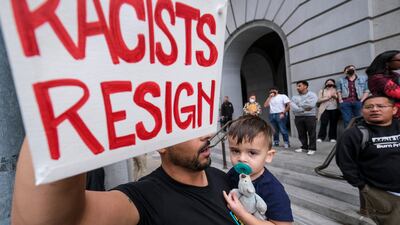 Shervin Aazami, holding his son Barrett and a sign, protests outside City Hall during the Los Angeles Council meeting. AP