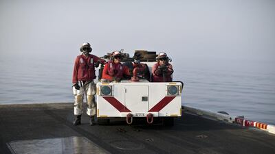 A crash and salvage team, wearing red shirts, stand ready as they observe flight operations.
