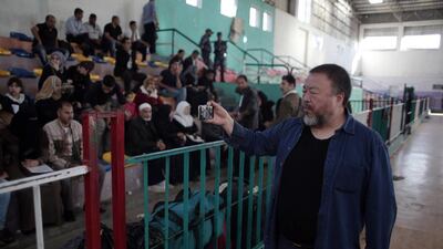 Chinese artist and activist Ai Weiwei, films Palestinians using his mobile phone, as they wait to travel through the Rafah border crossing with Egypt. Khalil Hamra / AP Photo