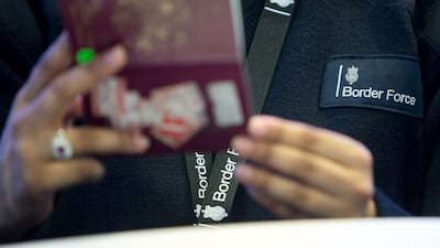 A Border Force officer checks a passport at Heathrow Airport. PA