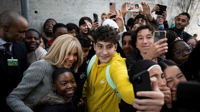 Brigitte Macron, the wife of the French President, poses with pupils for a selfie as she visits the public French language school, in Bern. AFP