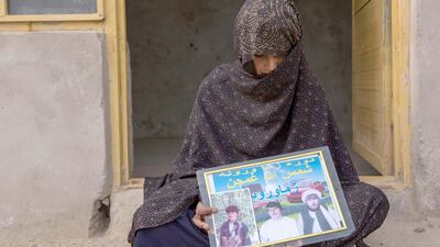 Covering her face, Khadija, 19, holds a photo of her three husbands: the Taliban fighter to the right, the police officer to the left, and her current husband in the middle. She lives outside of Helmand's provincial capital Lashkargar. Photo by Stefanie Glinski