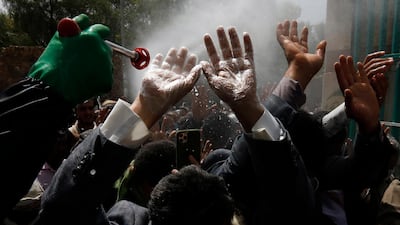 A Yemeni worker wearing a protective suit sprays disinfectant on the hands of people before they enter a cemetery during a funeral procession amid the ongoing coronavirus pandemic. EPA