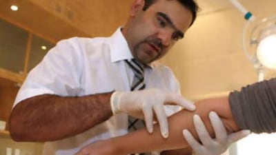 Dr Ali Singel checks the arm of Sophia Money-Coutts for patches of vitiligo at the Dermalase clinic in Dubai.