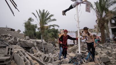 Palestinian girls next to a statue of a Palestinian boy, with the wings of an angel, in the ruins of a house destroyed in fighting with Israel in Deir Al Balah. AP
