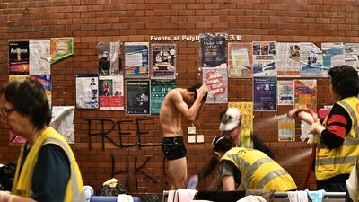 An anti-government protester (C) is showered down by volunteer medical workers after he was soaked in pepper-spray infused water by the police water cannon, inside the Hong Kong Polytechnic University in the Hung Hom district of Hong Kong on November 18, 2019. AFP / Anthony WALLACE