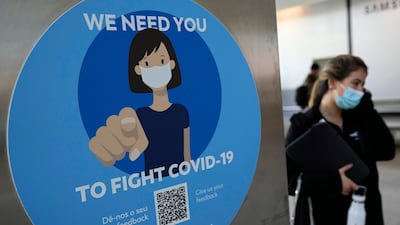 A woman wearing a face mask walks past a Covid-19 awareness sign at Lisbon's international airport. Portugal is bringing back some tight pandemic restrictions, less than two months after scrapping most of them when the goal of vaccinating 86% of the population against Covid-19 was reached. AP