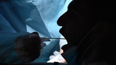 A healthcare worker collects a test sample from a motorist at a drive-through coronavirus testing center at MTO Shahmaghsoudi School of Islamic Sufism in Los Angeles, California. AFP