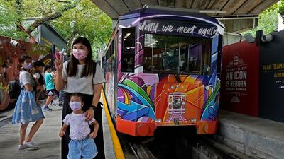 Passengers pose next to a Peak Tram on June 16, 2021. Hong Kong’s Peak Tram is a fixture in the memories of many residents and tourists, ferrying passengers up Victoria Peak for a bird’s eye view of the city’s many skyscrapers. Vincent Yu / AP Photo