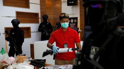 A plainclothes police officer holds a rifle as anti-terror police from Detachment 88 stand guard near explosive materials and other evidence confiscated from suspected militants during a media briefing at police headquarters in Jakarta on November 30, 2016. Beawiharta / Reuters