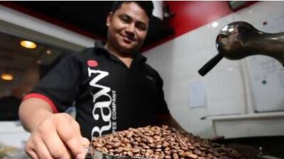 A staff member shows off a spoonful of roasted coffee beans at the Raw Coffee Company in Dubai. Pawan Singh / The National
