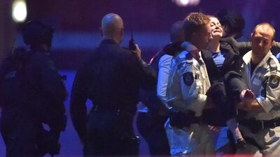 An injured hostage, right, is carried out of a cafe in the central business district of Sydney on December 16, 2014. Peter Parks/AFP Photo