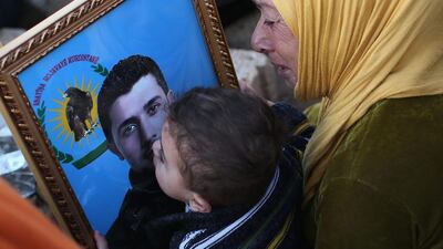 A boy kisses a photo of his father at a martyrs' cemetery for soldiers from the People's Protection Units (YPG), killed fighting ISIL.